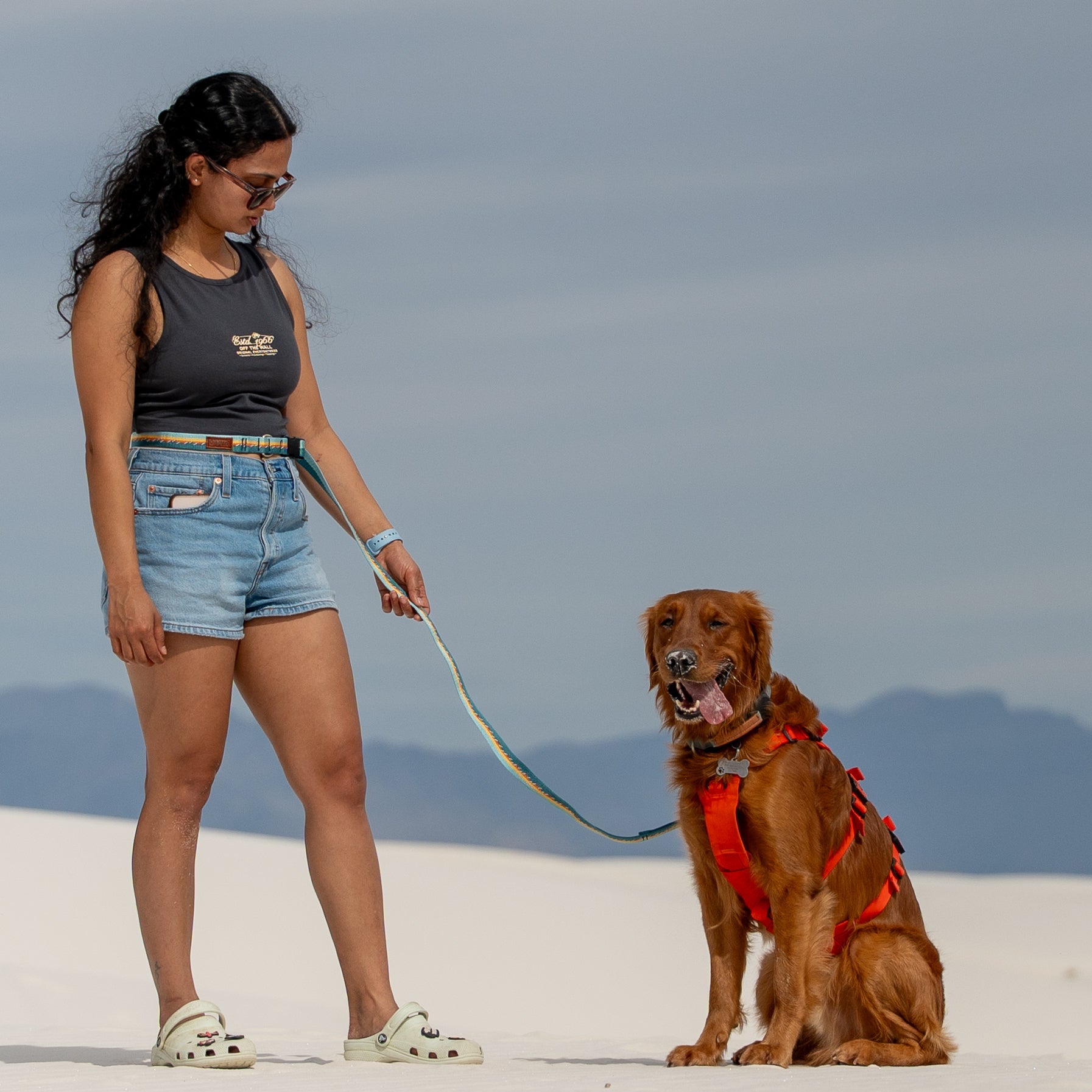 Woman standing with a dog on a leash in a desert landscape